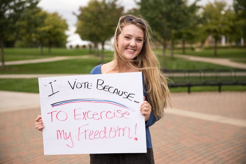 National Voter Registration Day Student holding a sign reading "I vote to exercise my freedom"
